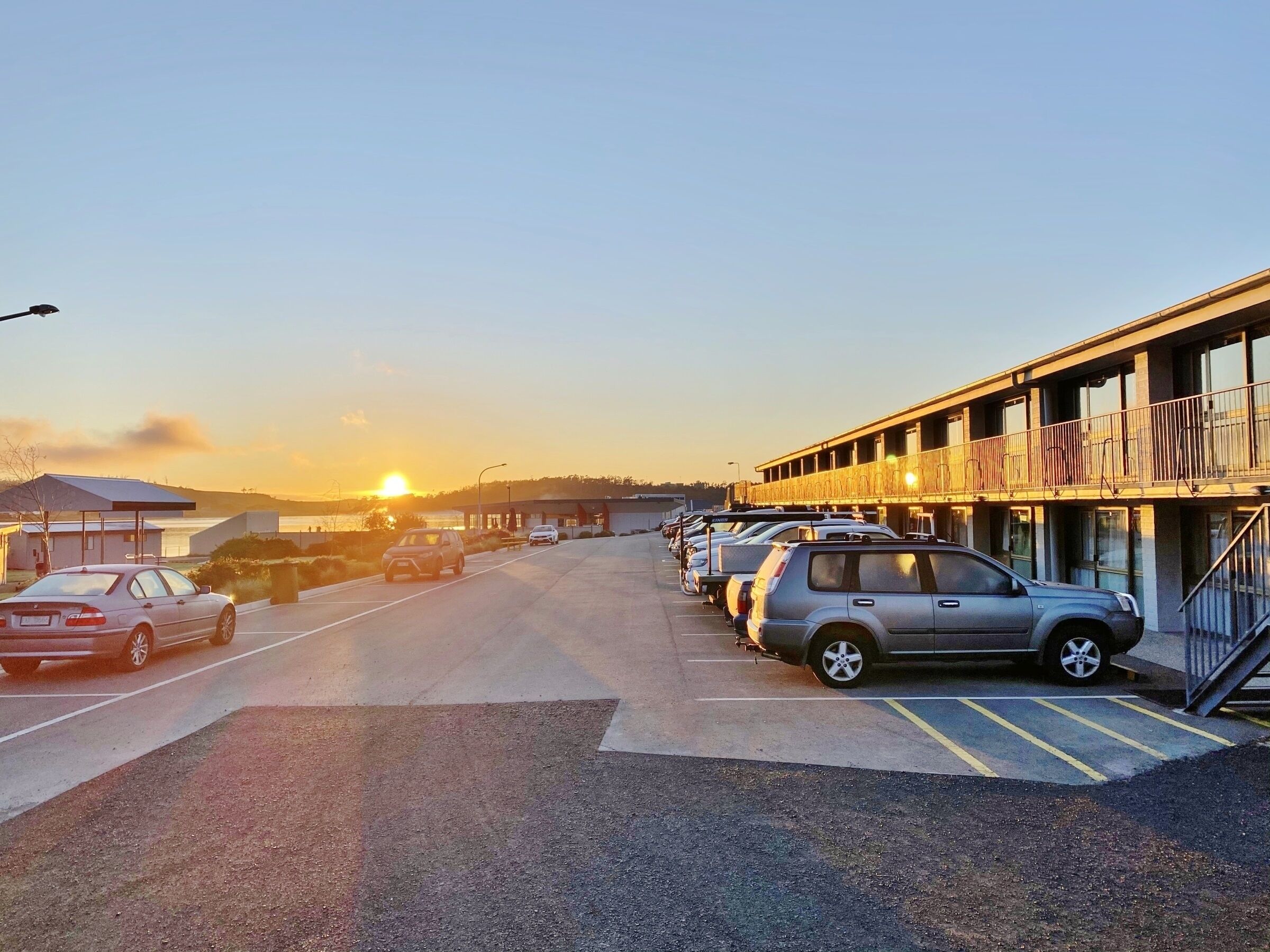 A parking lot with several cars parked in front of a building with balconies.