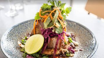Un plat agrémenté d’un quartier de citron vert, de chou rouge et d’oignons verts, le tout présenté dans une assiette à texture particulière.