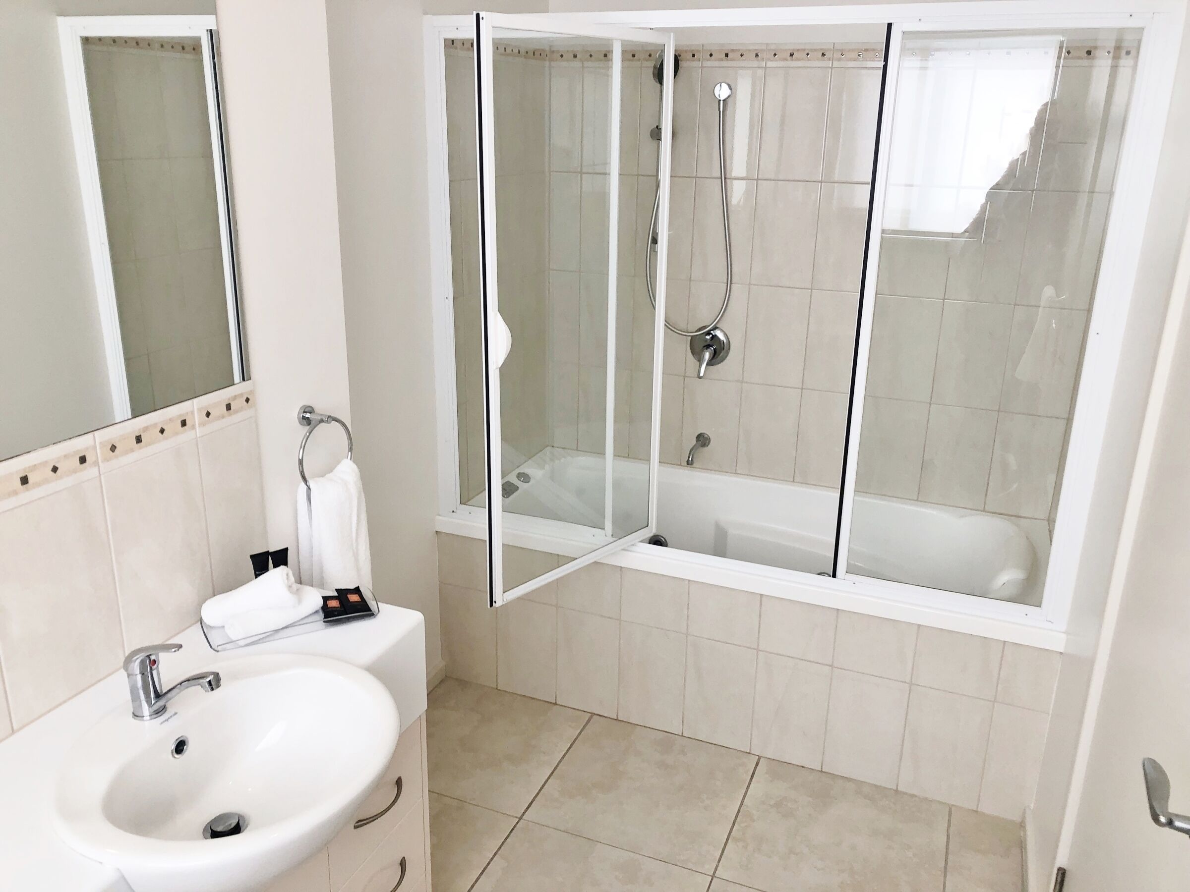Un baño moderno con un lavabo blanco, una ducha con mampara de vidrio y una bañera.