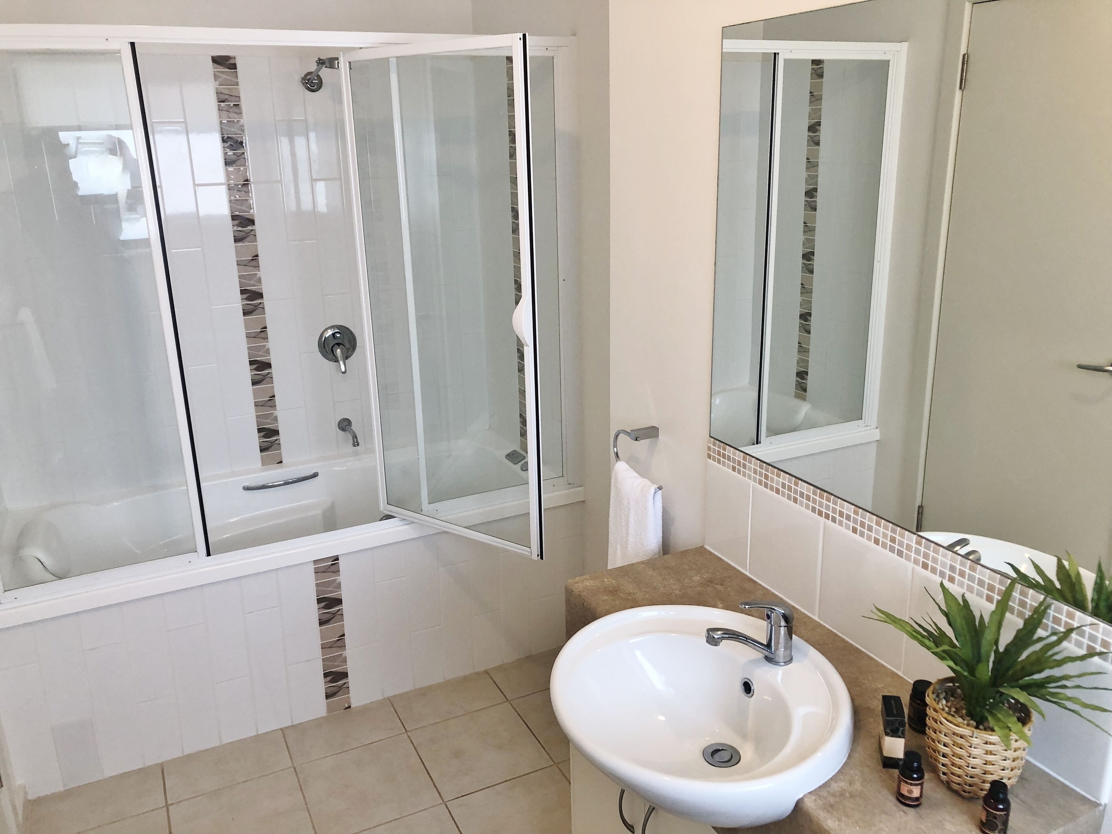 A modern bathroom with a glass-enclosed shower, a white sink, and a mirror above it.