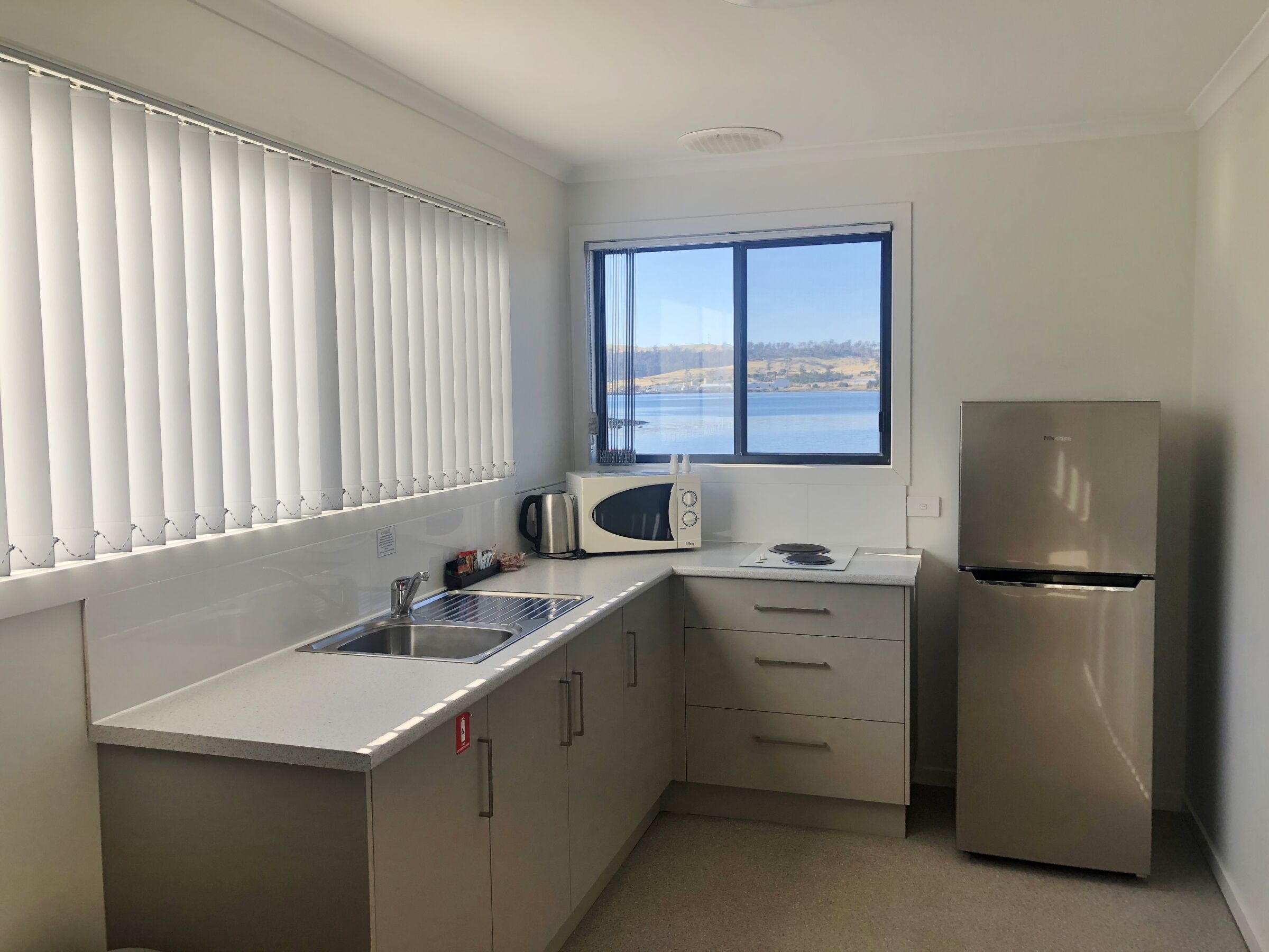 A compact kitchen with a stainless steel refrigerator, a microwave, and a sink.
