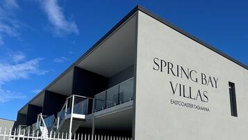 Welcome to Spring Bay Villas Eastcoaster Tasmania, featuring a flat roof and balcony with glass railings.