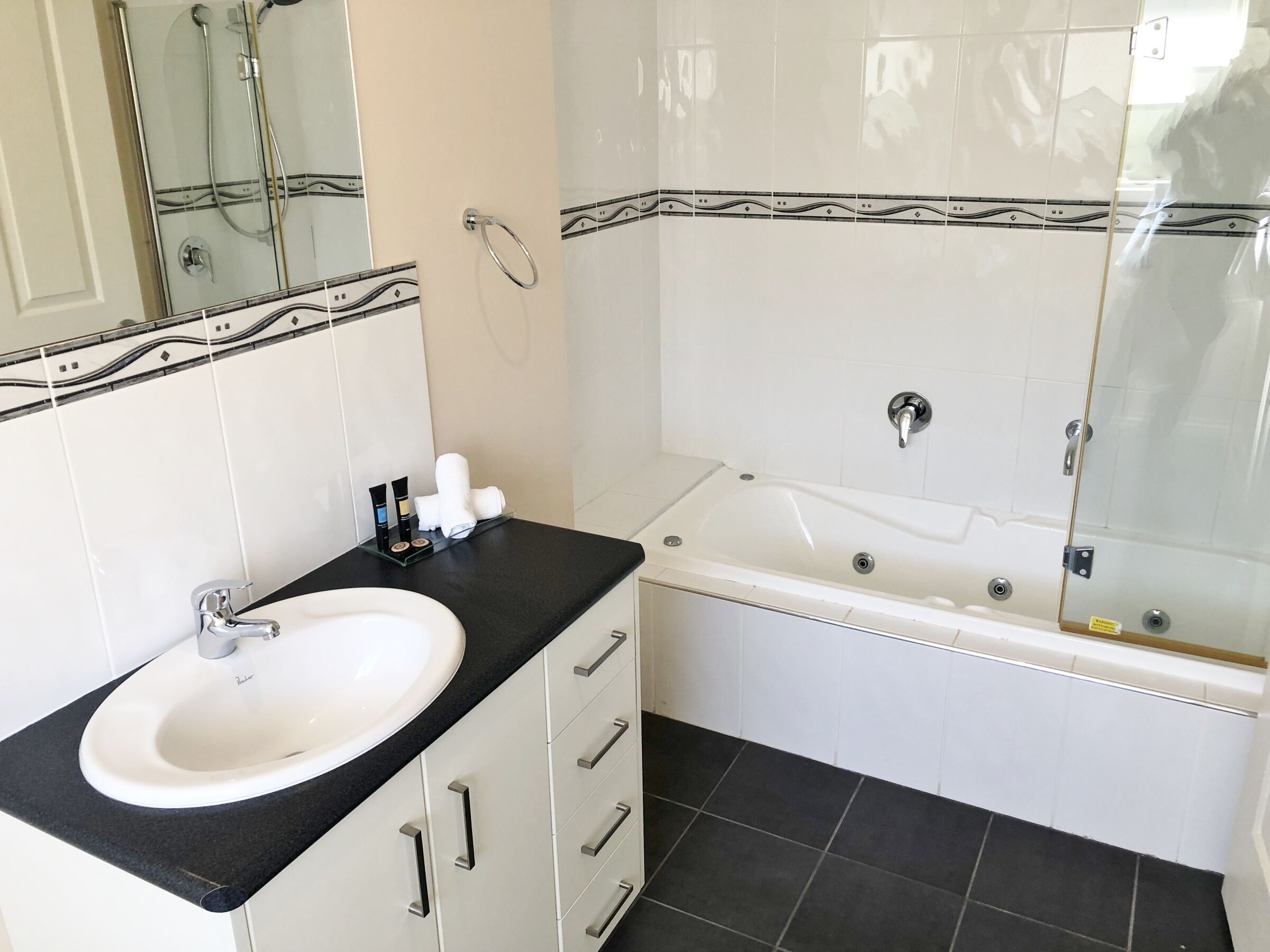 A bathroom with a white sink, black countertop, and a bathtub.