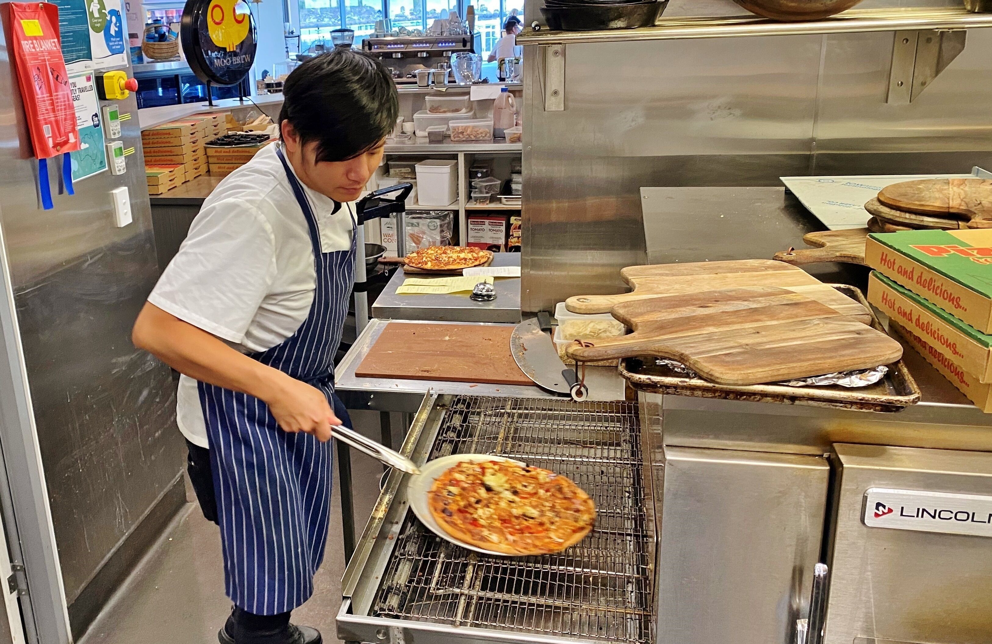 A kitchen with a griddle, pizza, and cooking utensils.