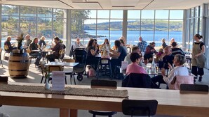 Een restaurant met grote ramen met uitzicht op het water en de heuvels.