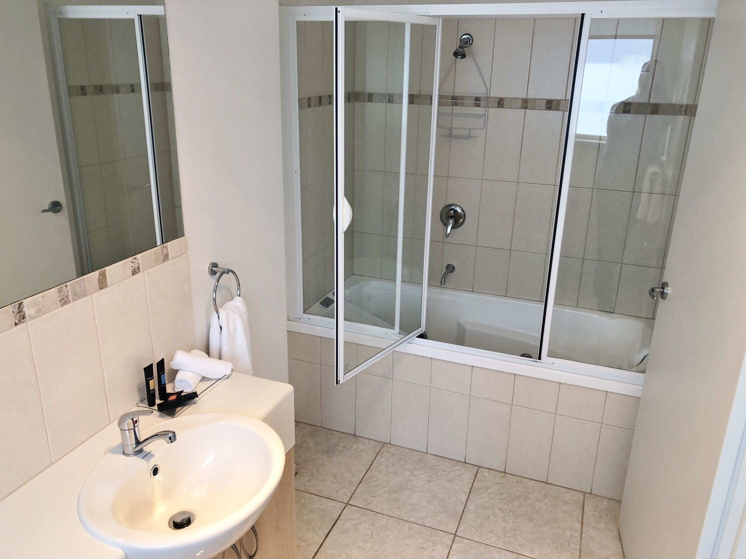 A bathroom with a sink, mirror, shower, and bathtub.