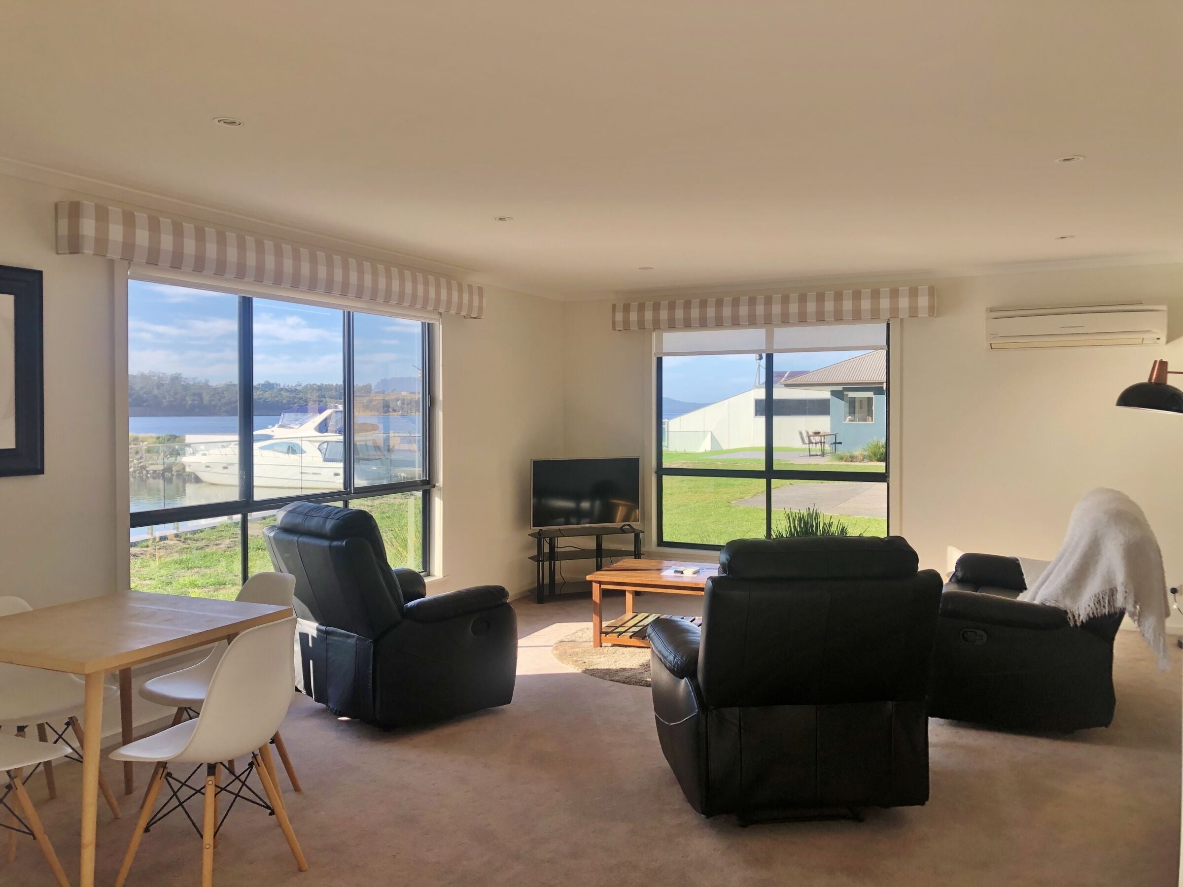 A spacious living room with large windows, a flat-screen TV, and comfortable seating.
