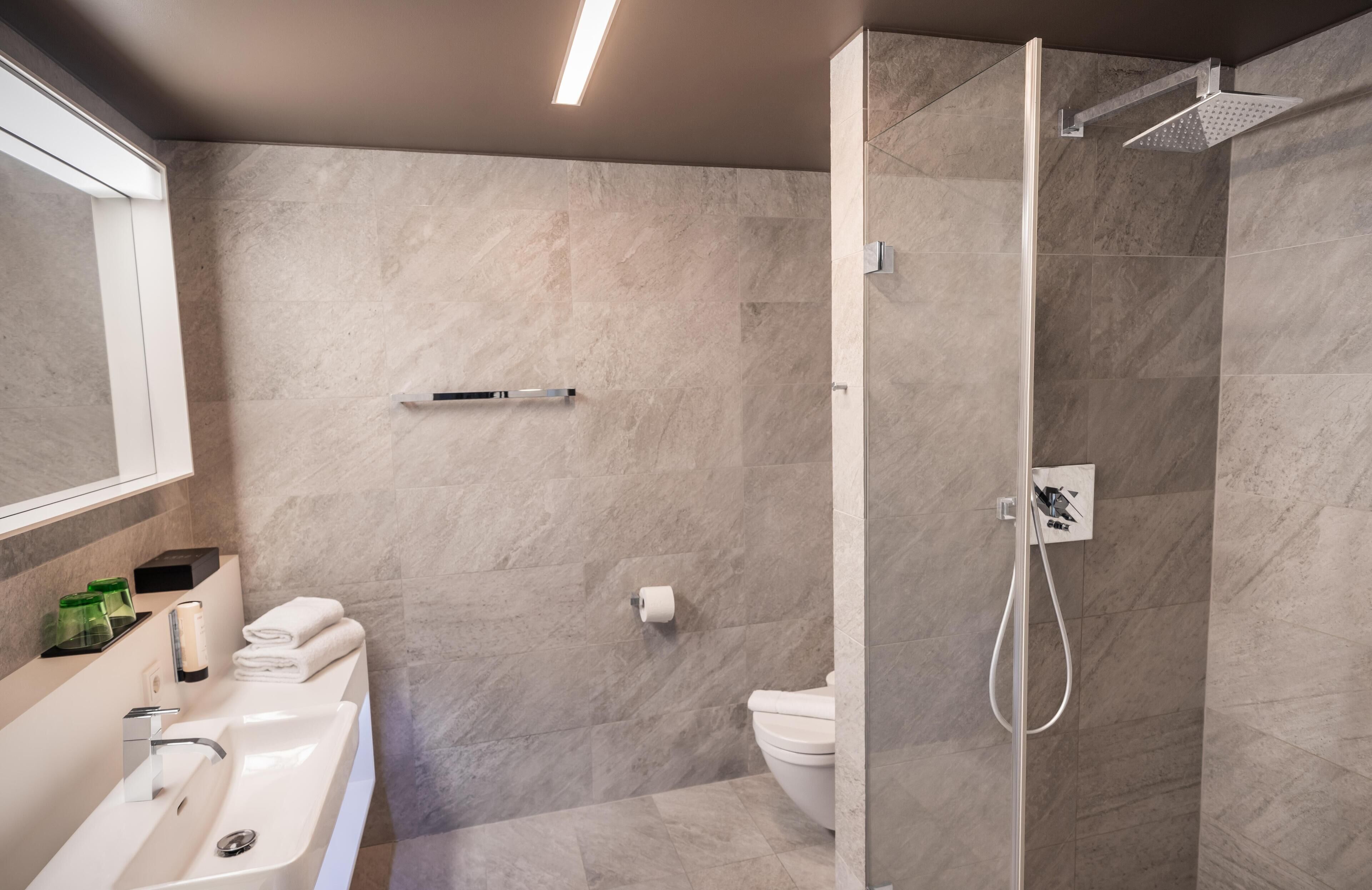 Un baño moderno con ducha, inodoro y lavamanos.