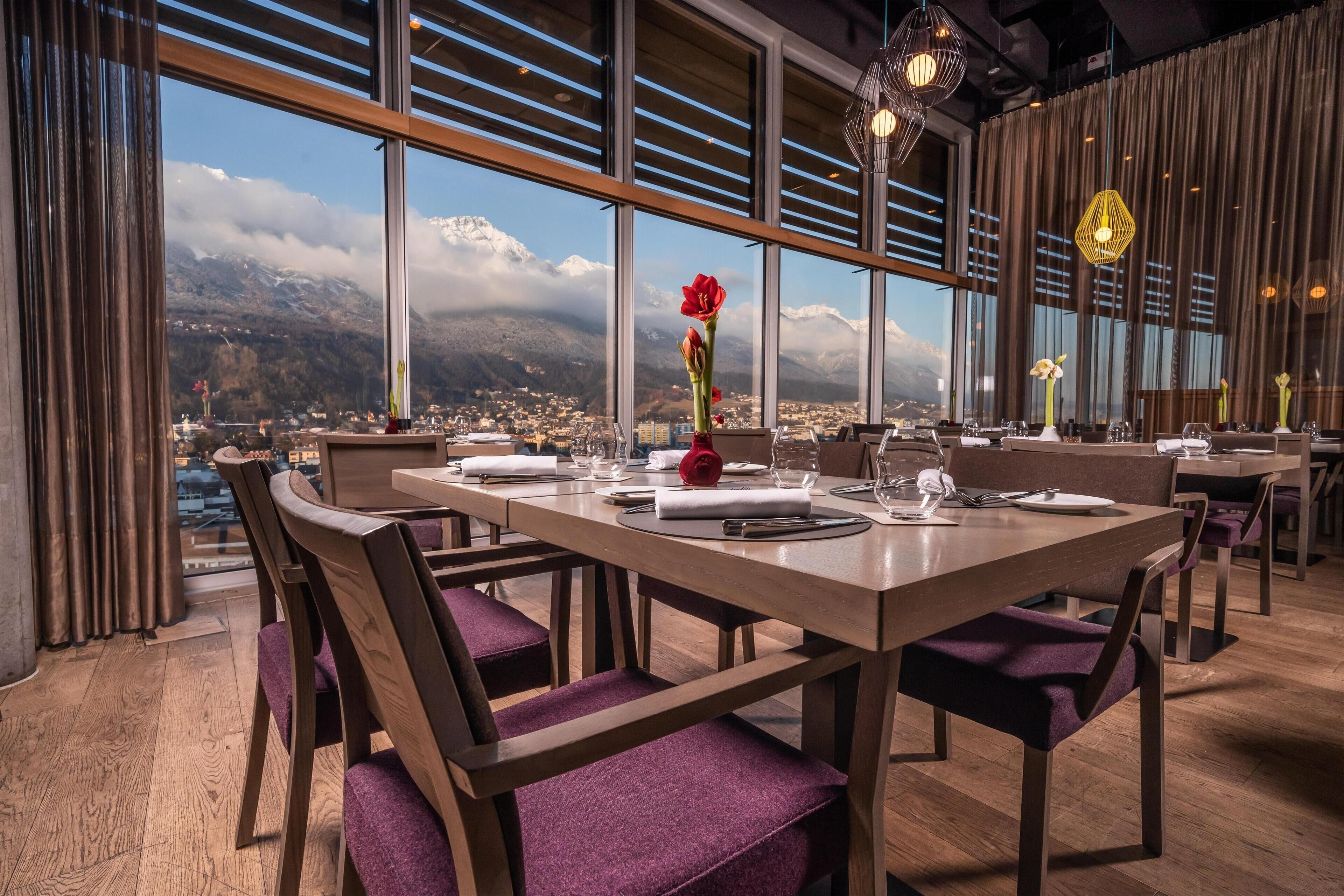 Comedor con vistas a las montañas, muebles de madera y una lámpara moderna.