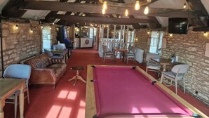 An indoor recreational area with a pool table, seating, and a bar area.