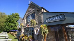 A stone building with a sign reading "The Riverside" and "ARKELL'S" on the side.
