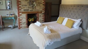 A bedroom with a large bed, a brick fireplace, and a desk with a chair.