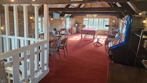 A cozy indoor space with a pool table, seating area, and a billiards machine.