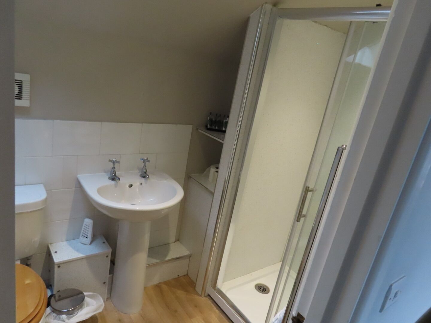 Une salle de bain avec un lavabo sur colonne, des toilettes et une douche à parois de verre.