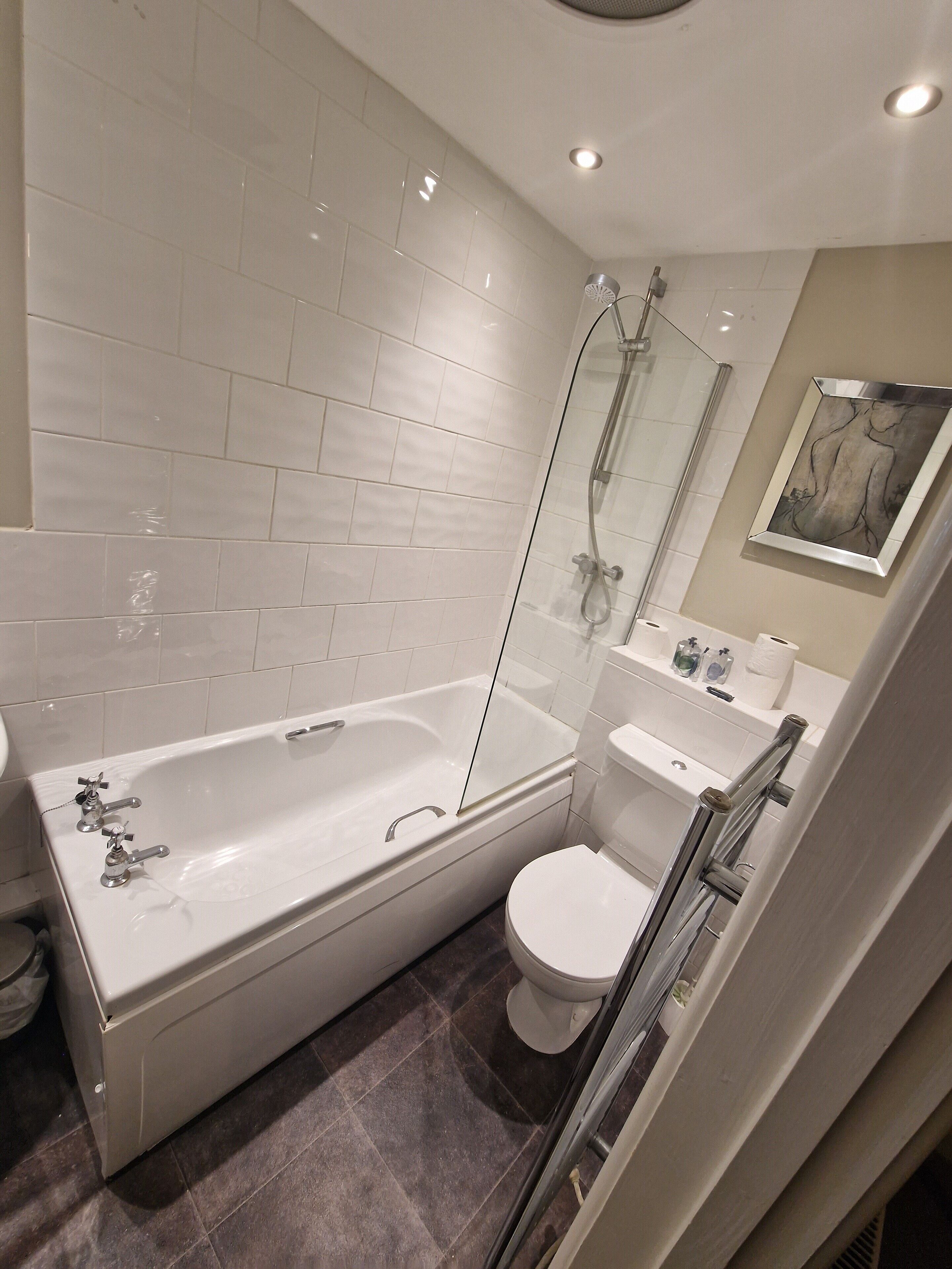 A modern bathroom with a large bathtub, a toilet, and a glass shower enclosure.