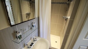 A bathroom with a sink, mirror, and shower. - The Saracens Head Hotel (Swindon)