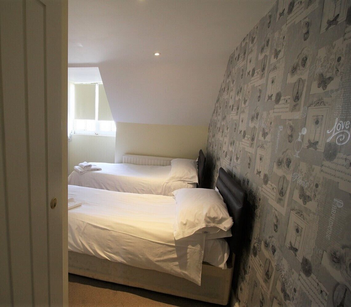 A bedroom with two beds, a window, and a wall with printed designs.