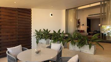A modern outdoor seating area with a round table, wicker chairs, and potted plants.