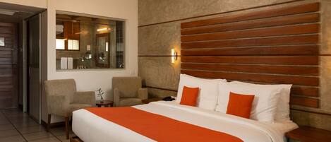 Una habitación de hotel con cama, zona de estar, espejo y ventilador de techo.