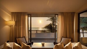 A hotel room with a balcony, a sofa, a table, and a lamp.