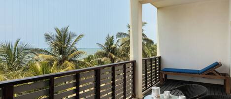 A balcony with a table, chairs, and a cushioned seat.