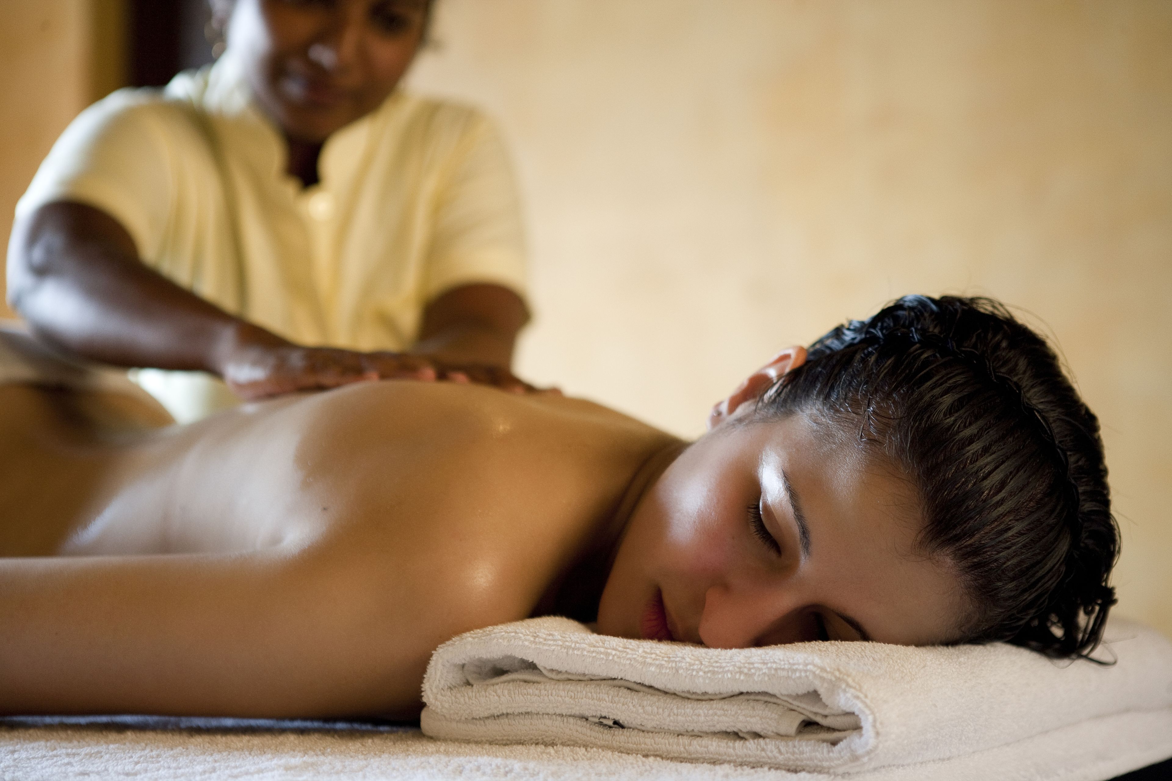 A person receiving a massage with a towel on the floor.
