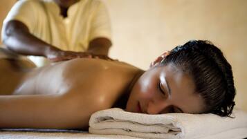 En person får massage medan hen ligger på en handduk på golvet.