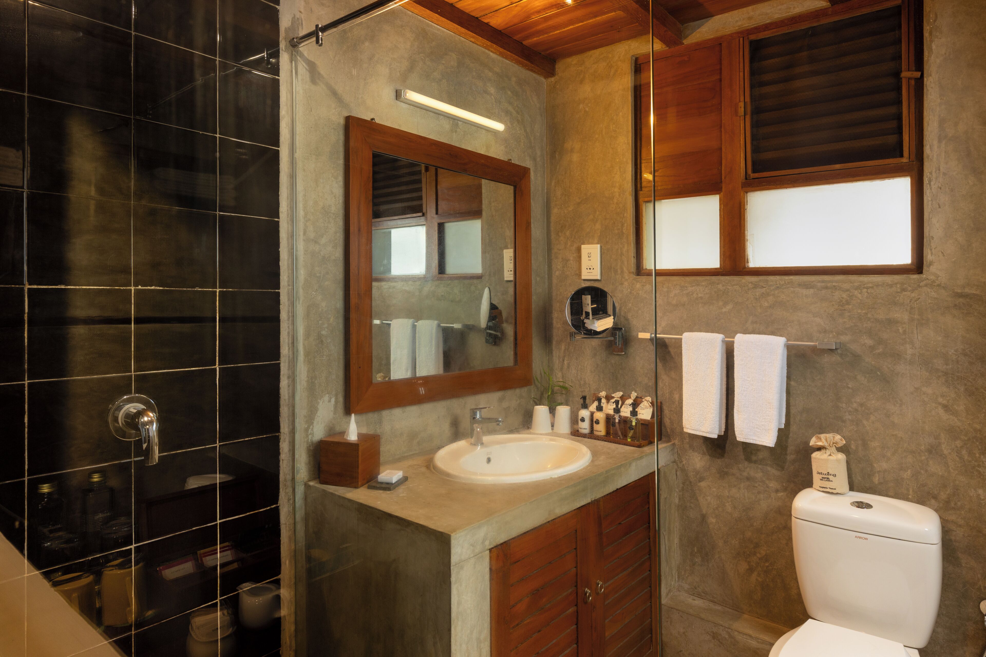 A bathroom with a large mirror, a sink, a toilet, and a shower area.