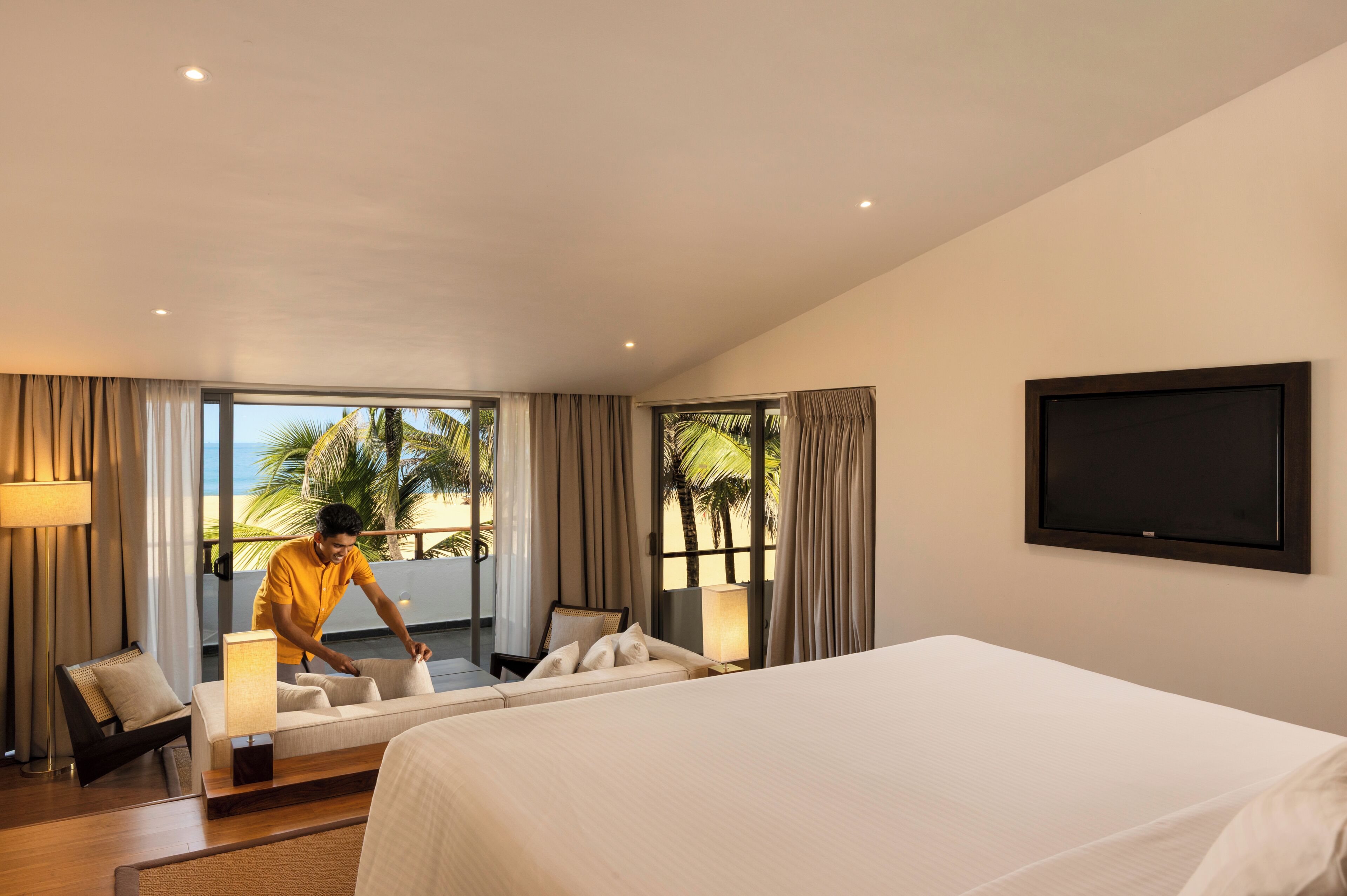 A hotel room with a bed, a chair, a desk, a lamp, and a TV.