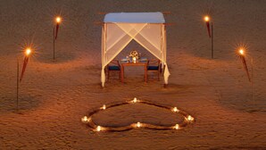 A beach setting with a tent and table, surrounded by lights.