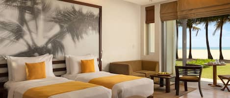 A hotel room with two beds, a bench, a chair, a table with fruits, and a view of the beach.