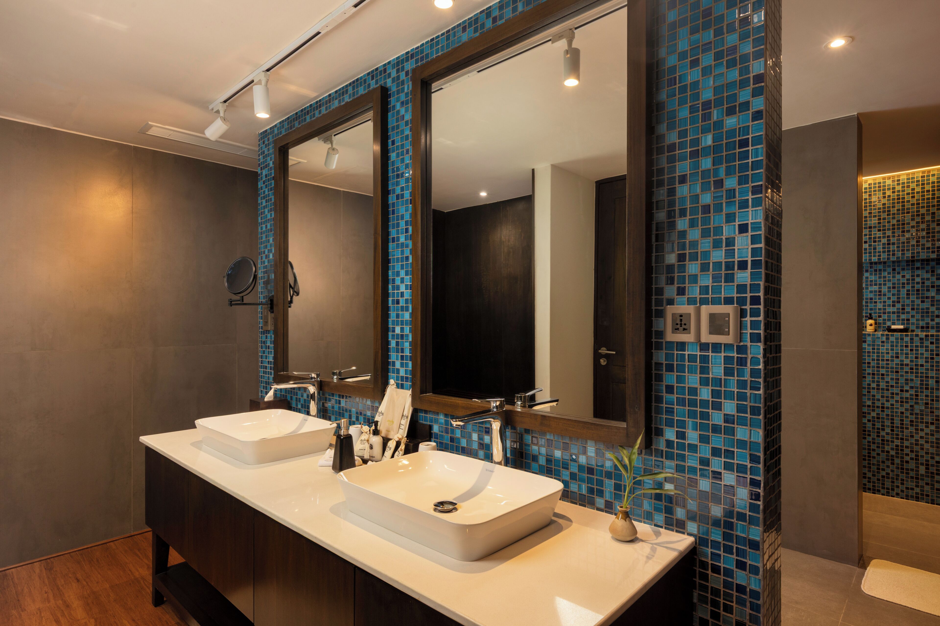 A modern bathroom with two sinks, a large mirror, and blue mosaic tiles.