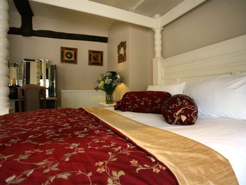 A hotel room with a large bed, a wooden headboard, and a mirror on the wall.
