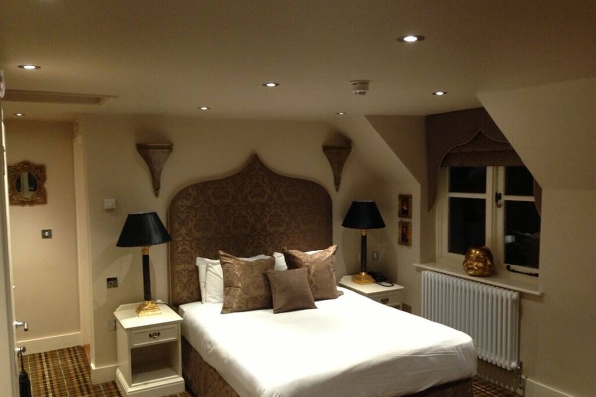Une chambre à coucher avec un grand lit, deux tables de chevet avec des lampes, un radiateur et une fenêtre donnant sur un beau paysage.
