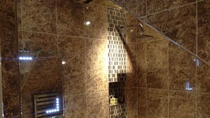A bathroom with a glass shower enclosure, a towel rack, and a mirror. - The White Hart Hotel (Halstead)