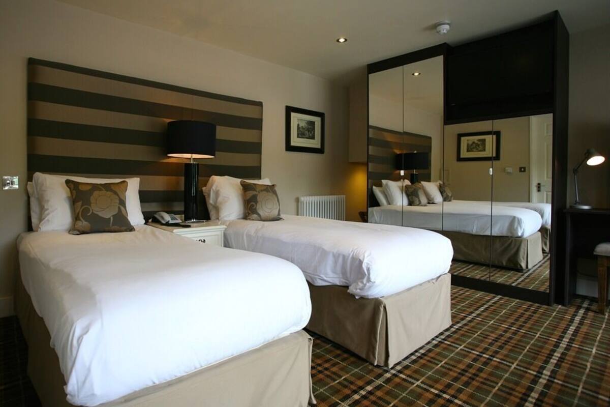 Une chambre d’hôtel avec deux lits, un grand miroir et un comptoir d’enregistrement.