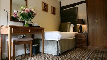 A bedroom with a bed, bedside table, lamp, dresser, mirror, and a plaid-patterned floor.