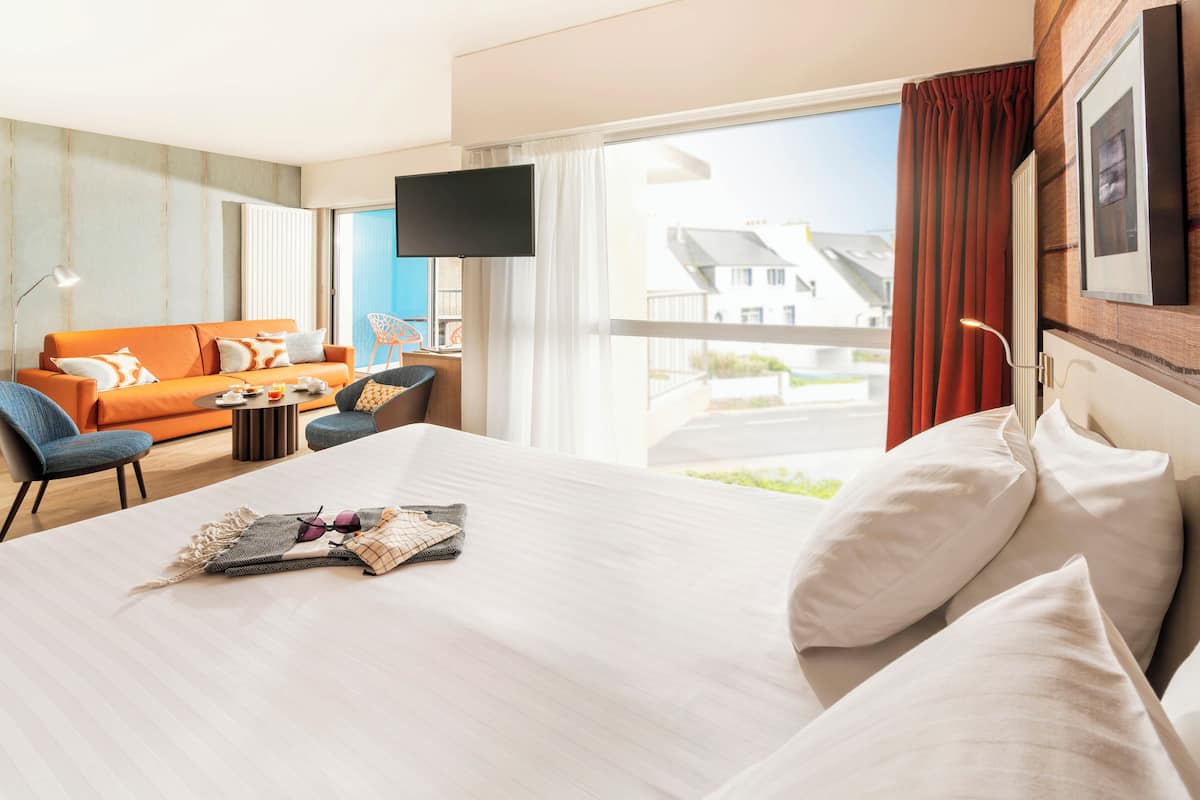Een hotelkamer met een bed, een bank, een stoel, een tafeltje en een televisie.