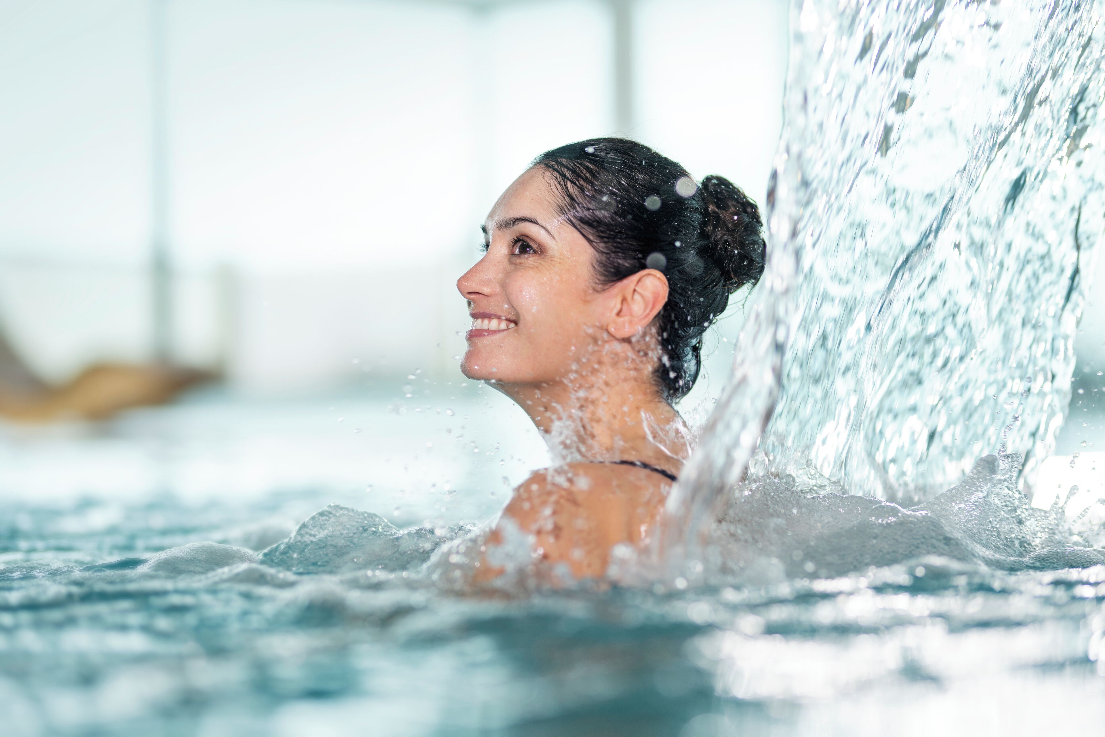 A person in a hot tub with water splashing around them.