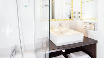 A modern bathroom with a glass-enclosed shower, a white sink, and a dark wooden vanity.