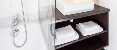 Une salle de bain moderne avec une douche à parois de verre, un lavabo blanc et un meuble-lavabo en bois foncé.