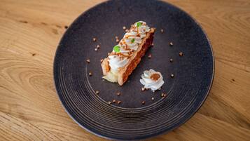 Un postre sobre un plato oscuro, con una mesa de madera de fondo.
