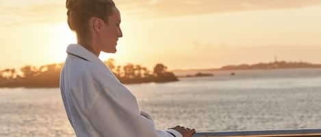 A person standing by a railing overlooking a body of water during sunset.
