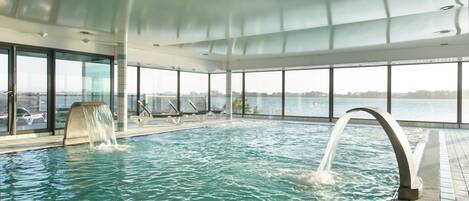 Ein Innenpool mit freiem Blick auf das Wasser draußen, großen Fenstern und einem modernen architektonischen Design.