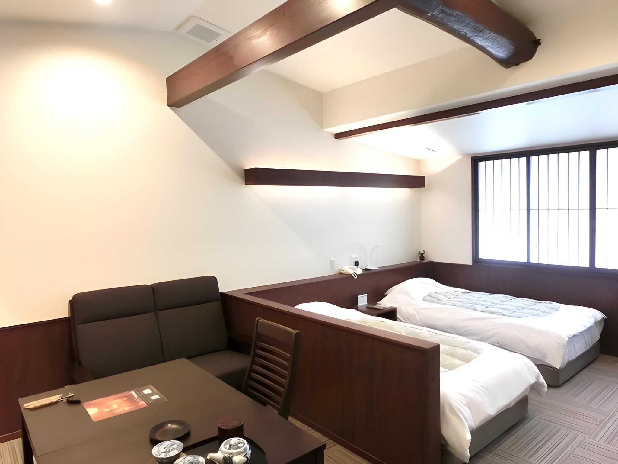A compact hotel room with a bed, a small desk, and a window.