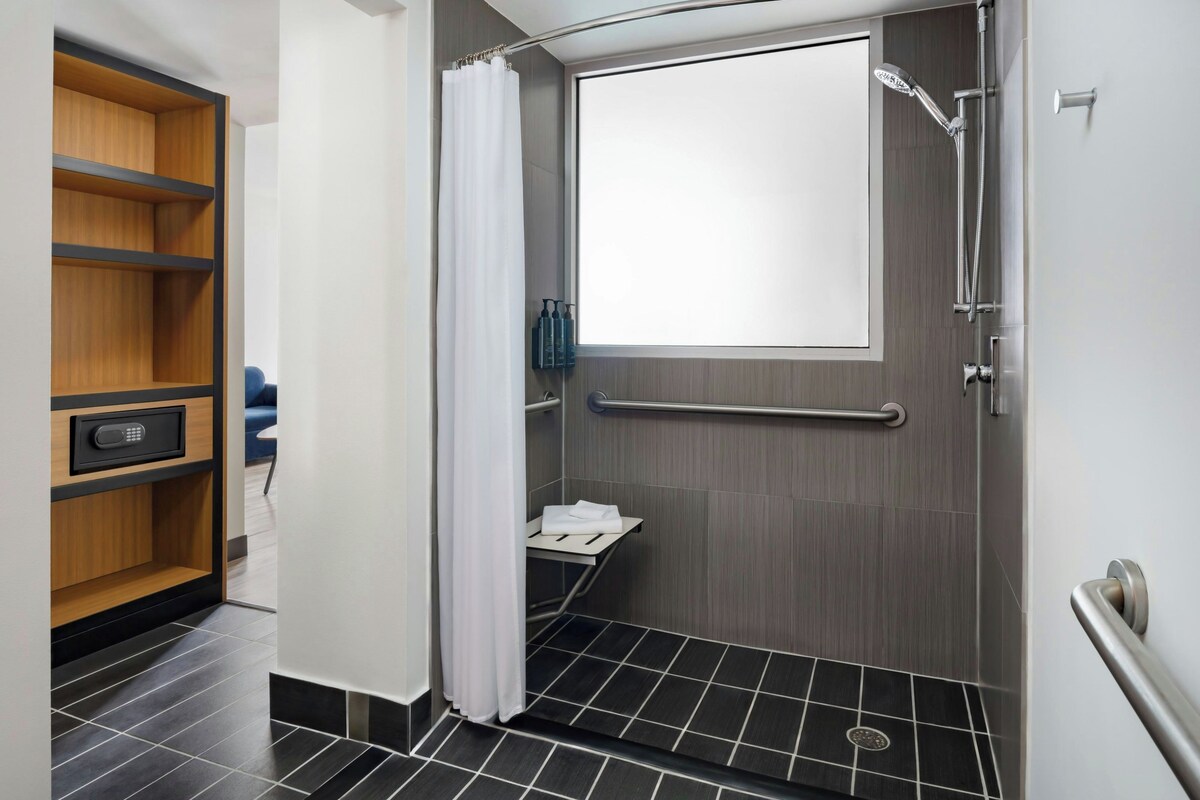 Un baño moderno con ducha, inodoro y un pequeño estante con artículos de aseo.