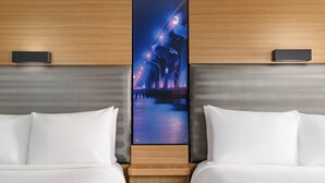 A hotel room with two beds, a nightstand, and a large framed picture of a bridge at night. - Aloft by Marriott Miami - Brickell (Miami)