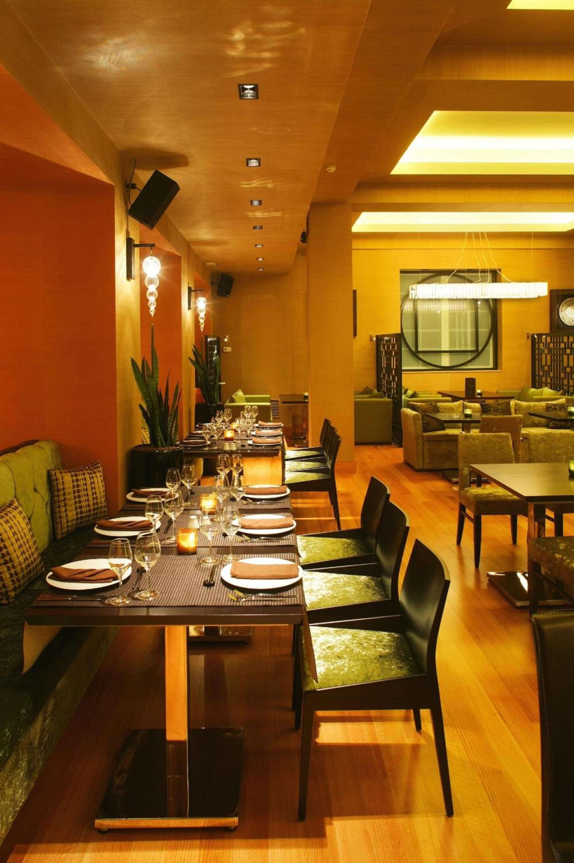 A restaurant with a long dining table set for a meal, surrounded by chairs and a sofa.