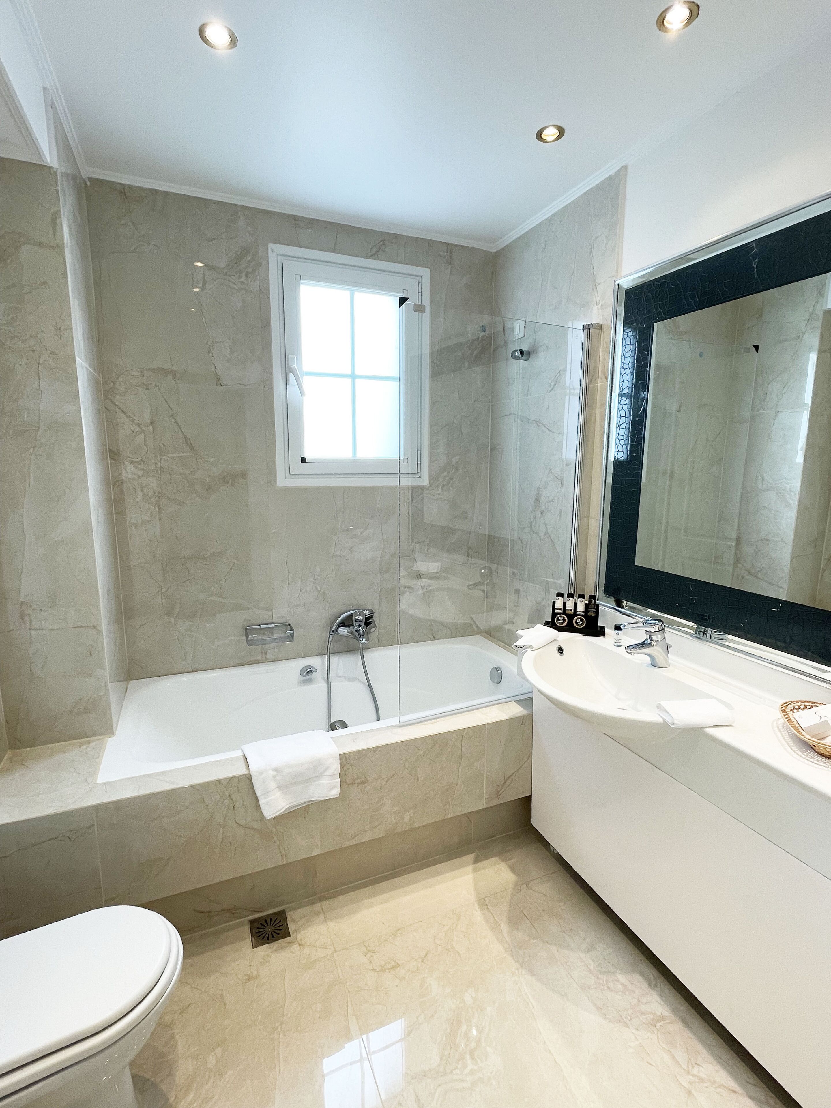 Un baño moderno con una bañera, un espejo grande y un inodoro.