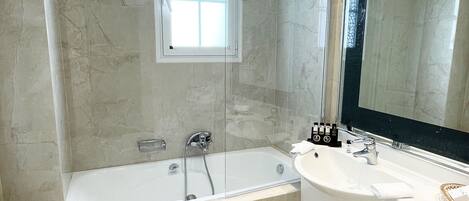 Un baño moderno con una bañera, un espejo grande y un inodoro.